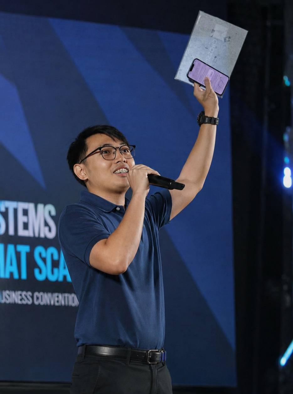 Ken Villarias speaking on stage at a business convention
